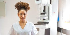 Smiling woman nurse with a mammography machine in background