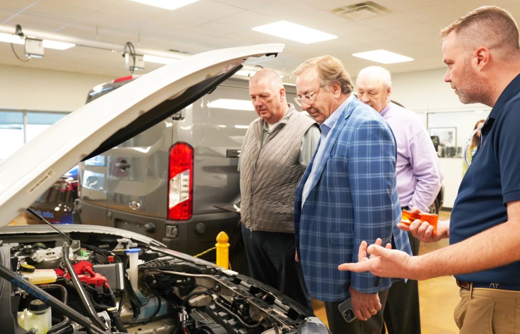 Three people are looking at EV engine