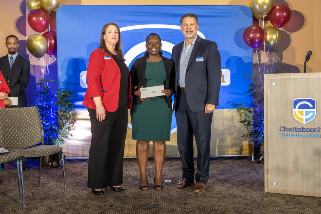 The 2025 EAGLE winner is standing on stage with Chatt Tech Interim President Heather Pence and Trustees Board Chair Marty Hughes.