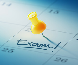 A push pin in the day of a calendar that reads, "Exam!"